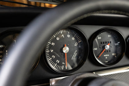 Close-up of a car's dashboard with speedometer and tachometer gauges.