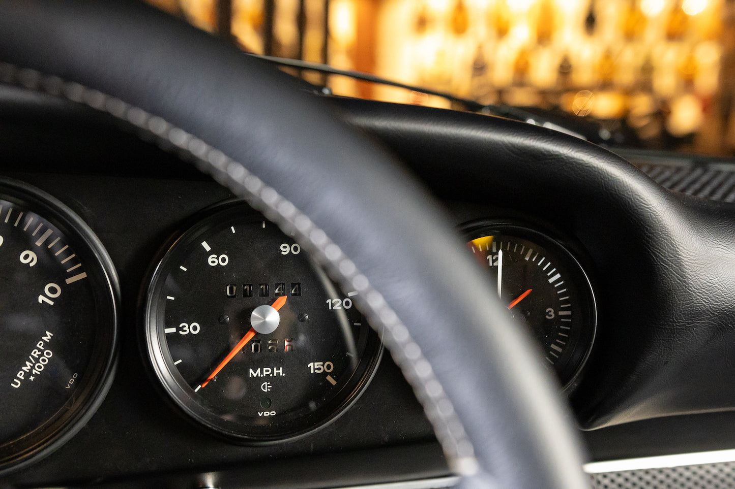 Close-up of a car dashboard with gauges and steering wheel.