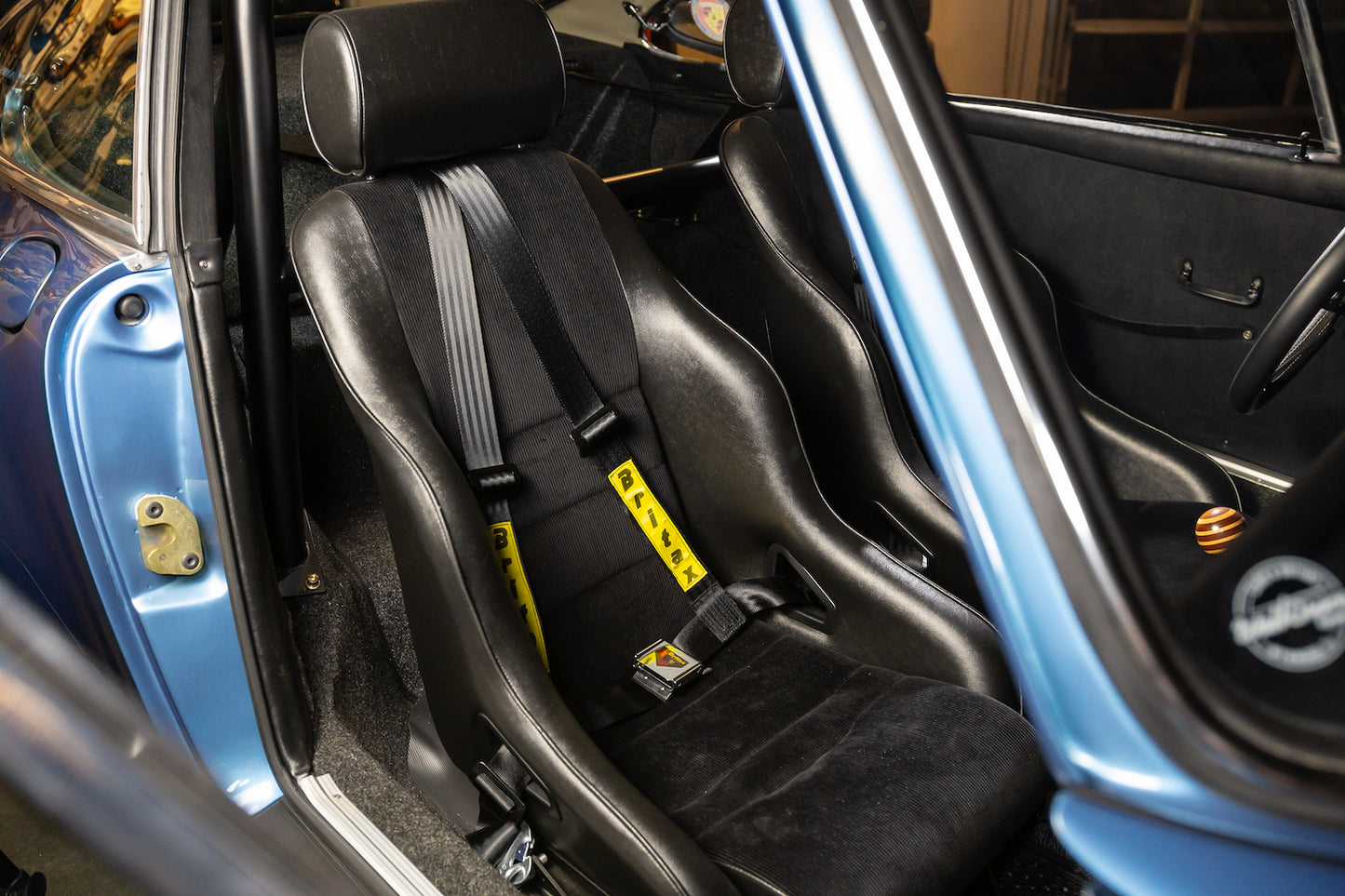 Car interior with black racing seats and visible seat belts.