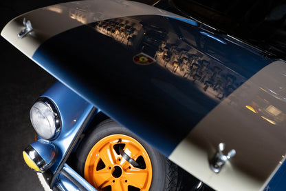 Close-up of a car's front wheel and fender with a blue and silver color scheme.