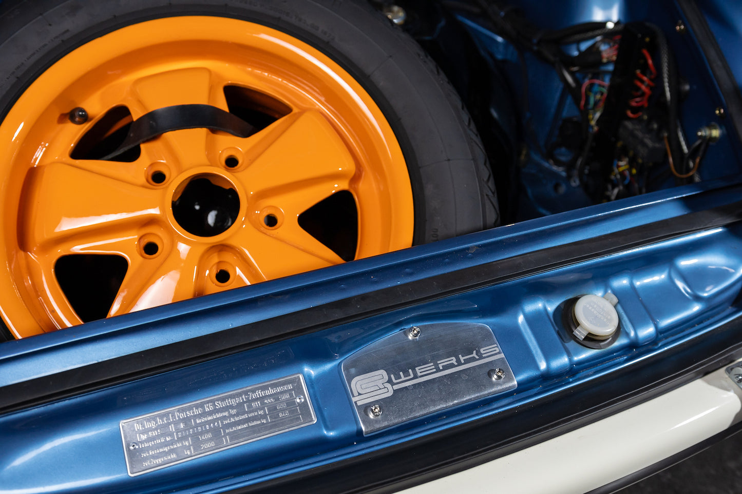 Close-up of a blue car with orange rim and 'Brembo' branding.