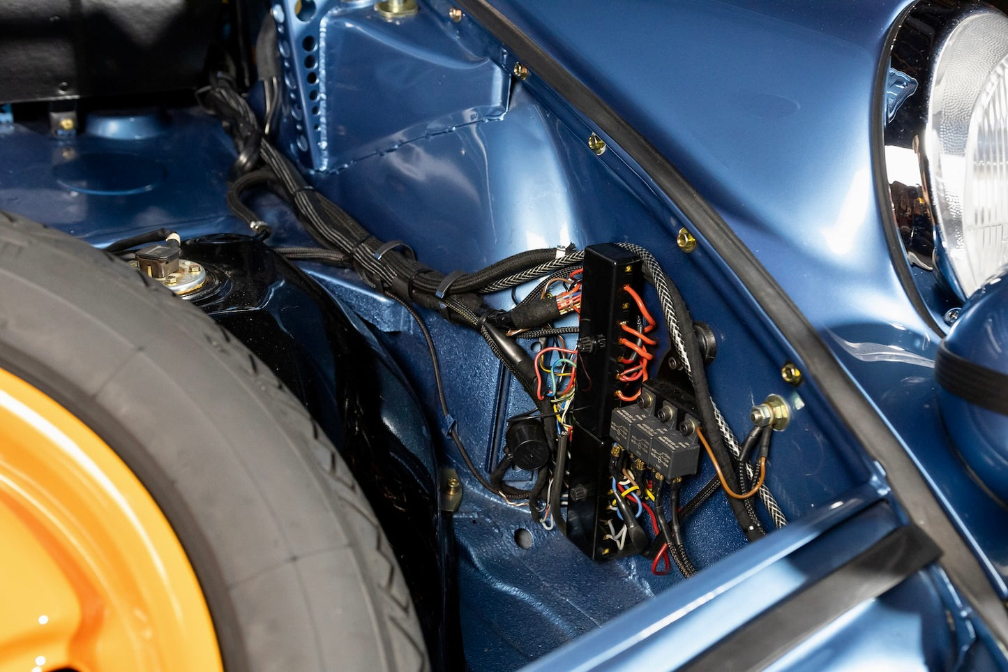 Close-up of a blue vehicle's undercarriage with visible wiring and components.