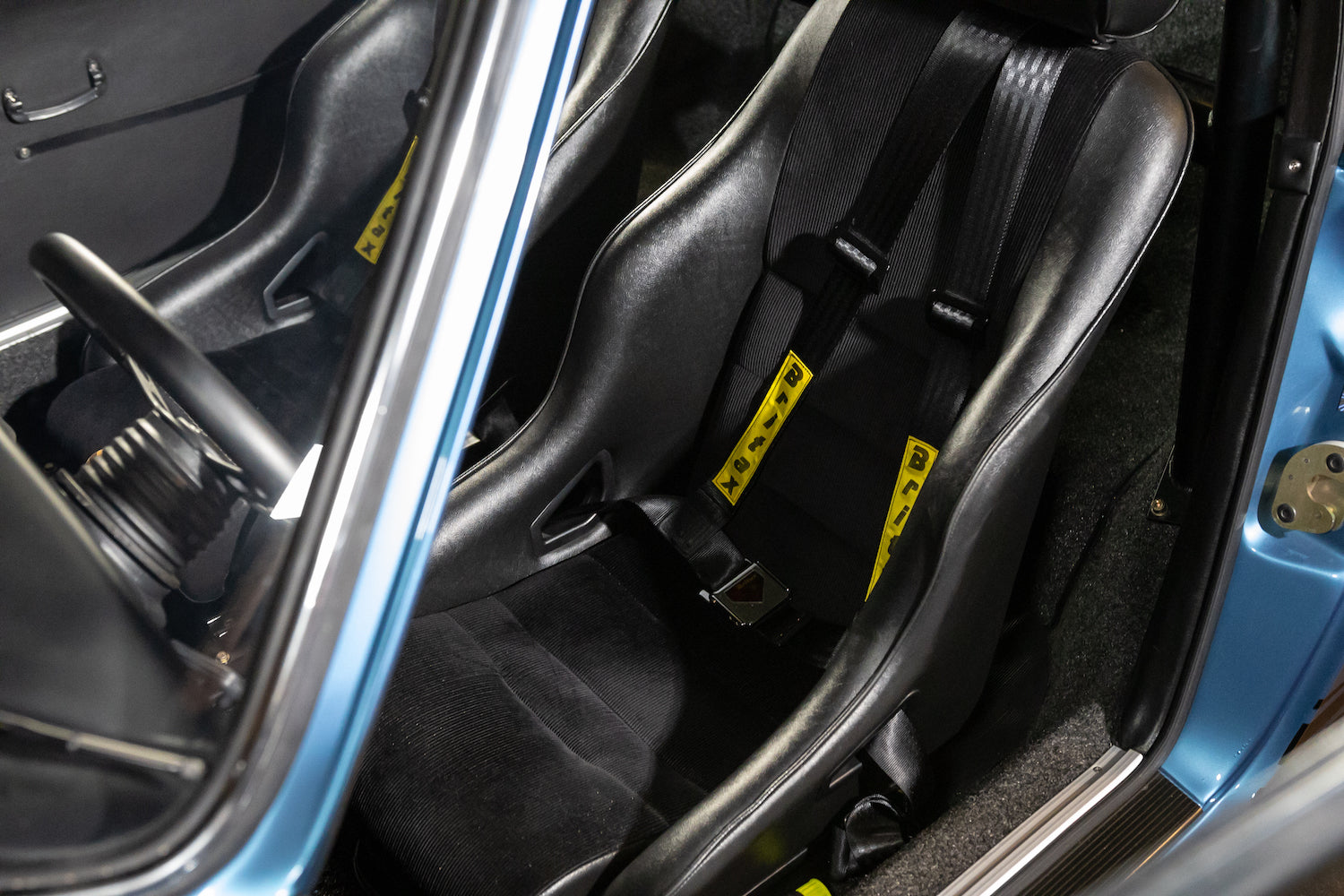Close-up of a car's interior with black racing seats and visible seat belts.