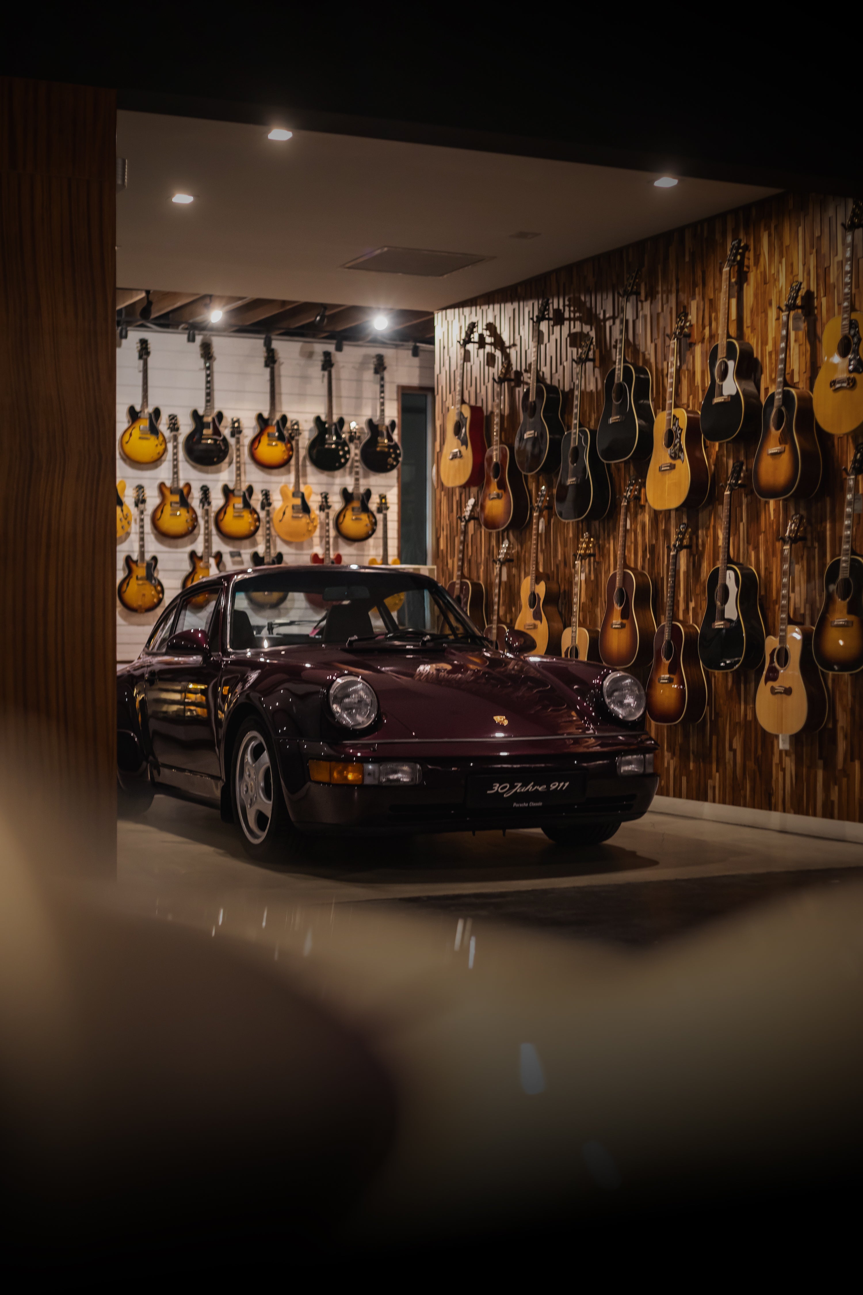 Porsche 911 parked next to guitar wall at Walt Grace Vintage
