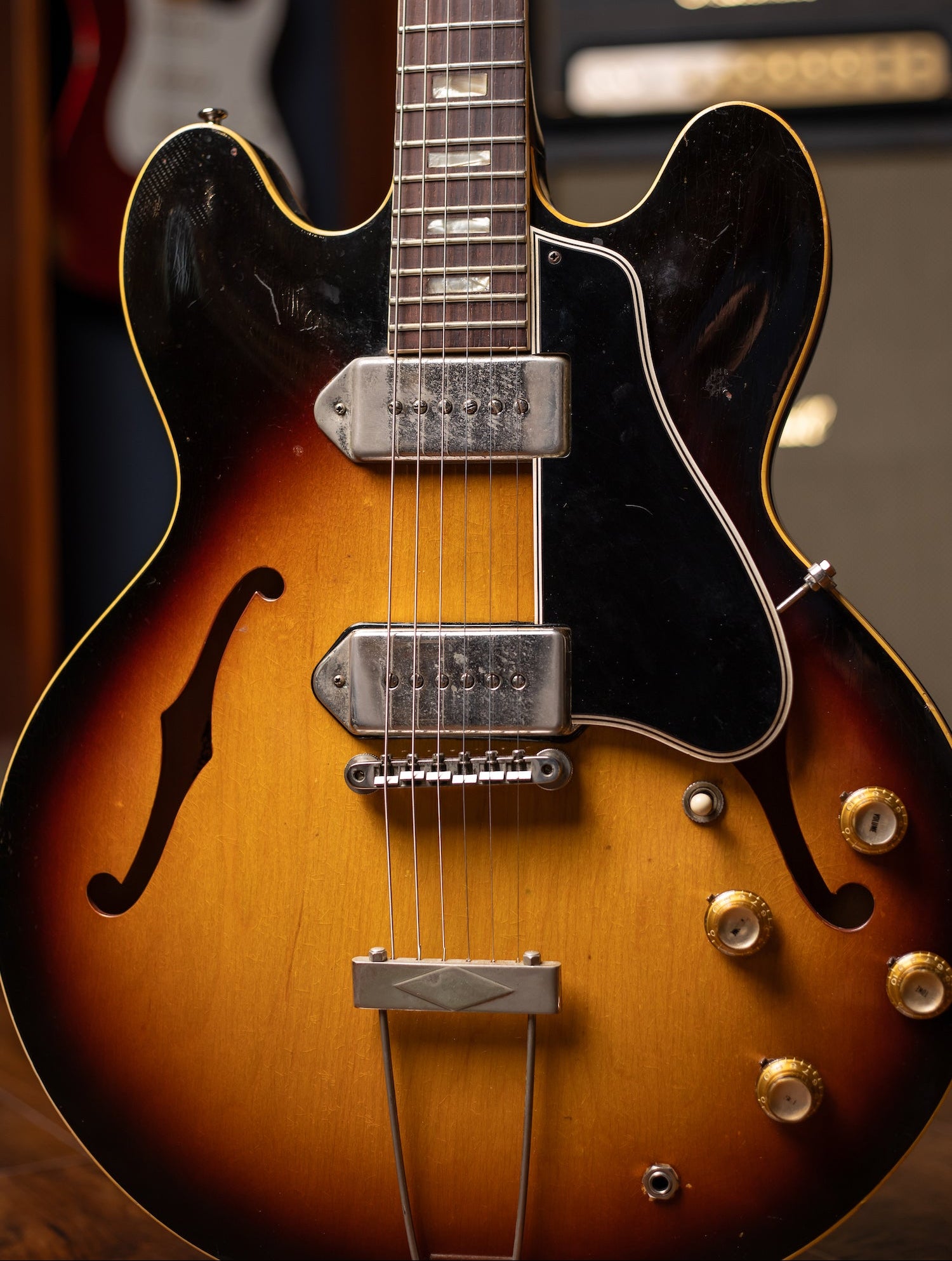 Close-up of a vintage electric guitar with a blurred amplifier in the background