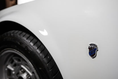 Close-up of a car emblem on a white vehicle