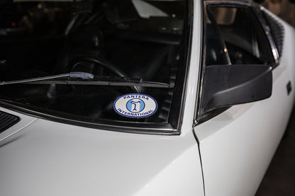 Close-up of a white car with a 'Panthera International' logo on the windshield wiper.