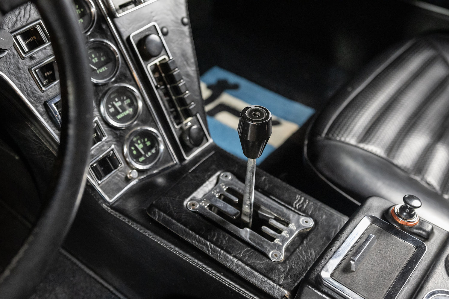 Close-up of a car's gear shift lever and dashboard controls.