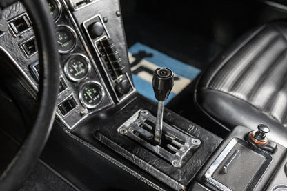 Close-up of a car's gear shift lever and dashboard controls.