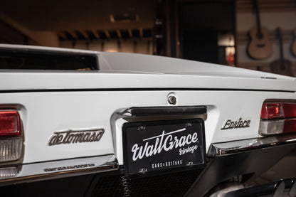 White car with 'Wall Grace' license plate in a garage setting