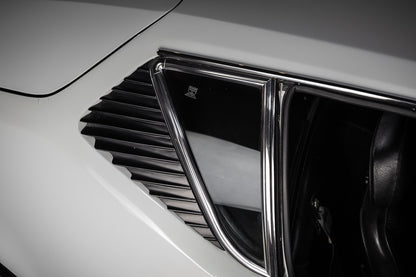 Close-up of a car's air vent and emblem on a white background