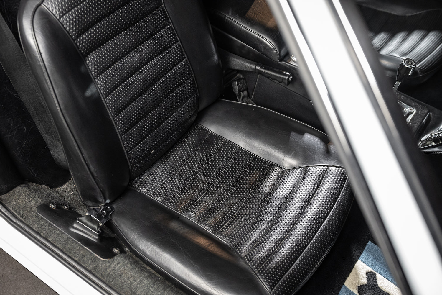 Close-up of a car seat with a textured pattern, showing the interior design and materials.