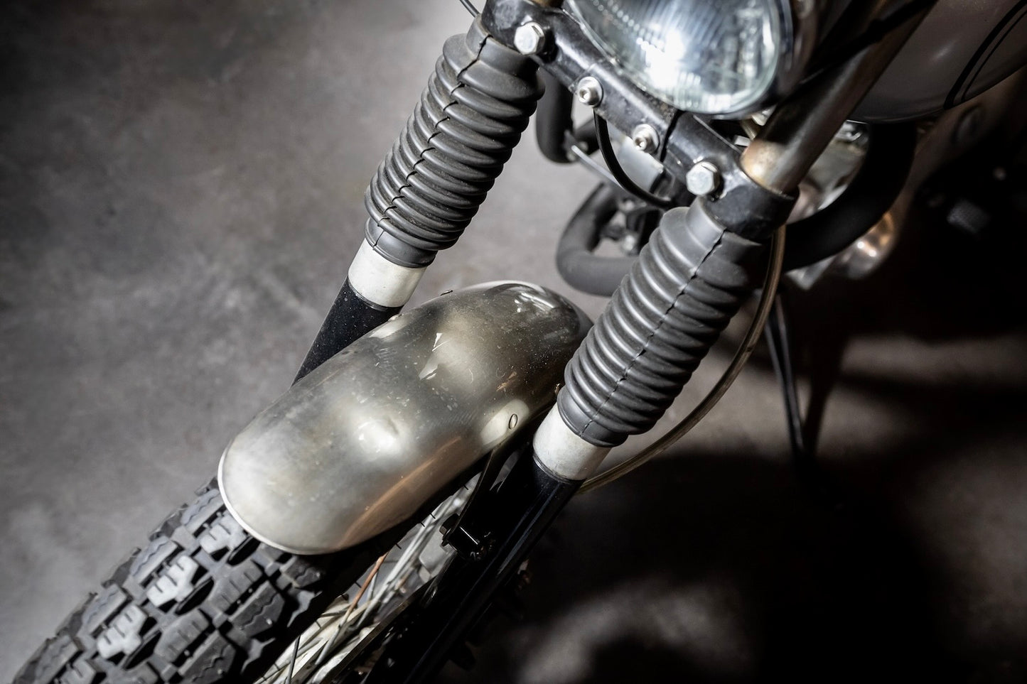Close-up of a motorcycle's headlight and front wheel on a dark background