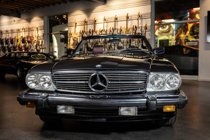 Black Mercedes-Benz car in a showroom with guitars on the wall.
