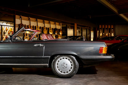 Vintage convertible car in a showroom with guitars on display in the background