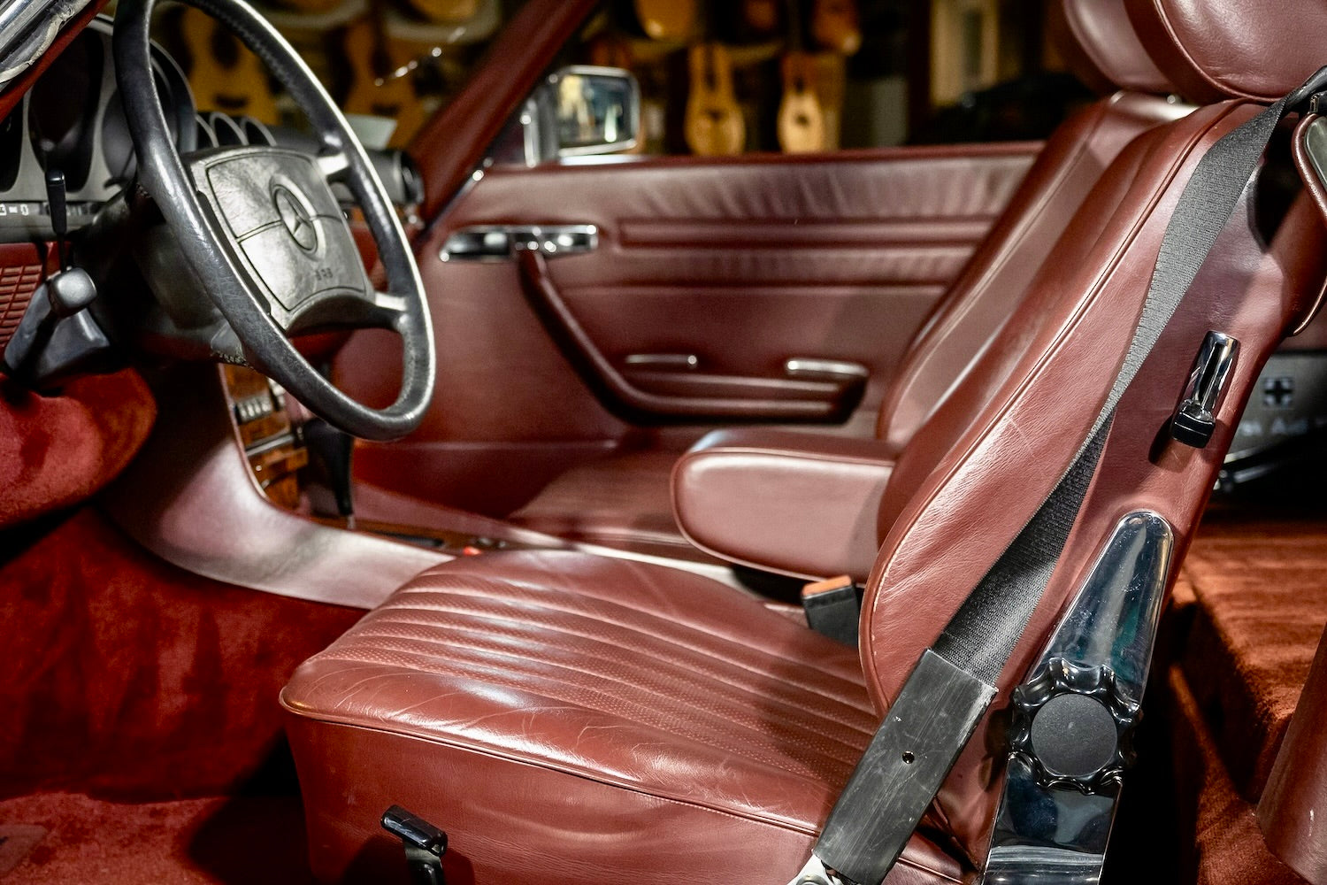 Close-up of a car's brown leather interior with steering wheel and seat belts.