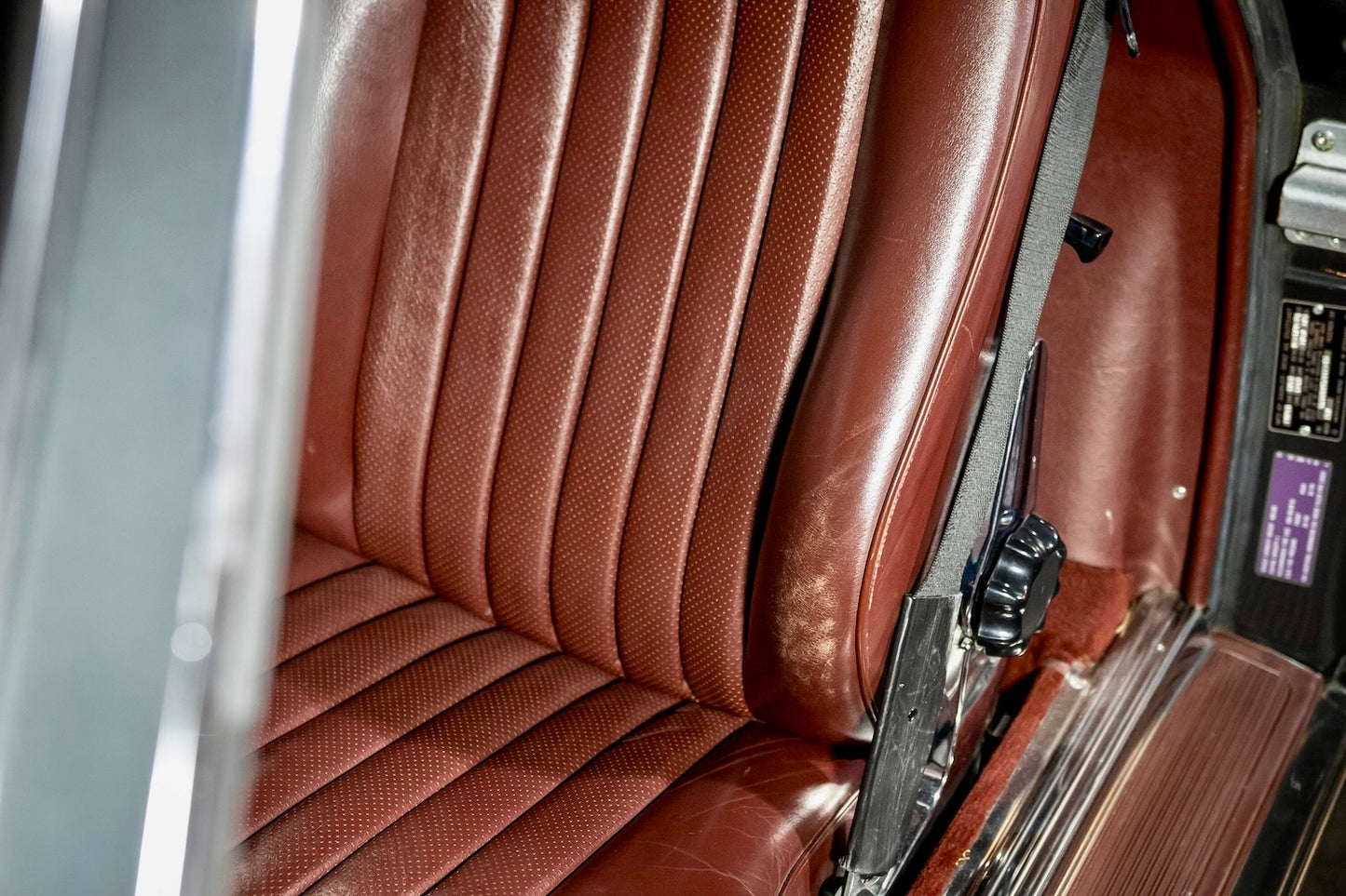 Close-up of a brown leather car seat with a seatbelt.