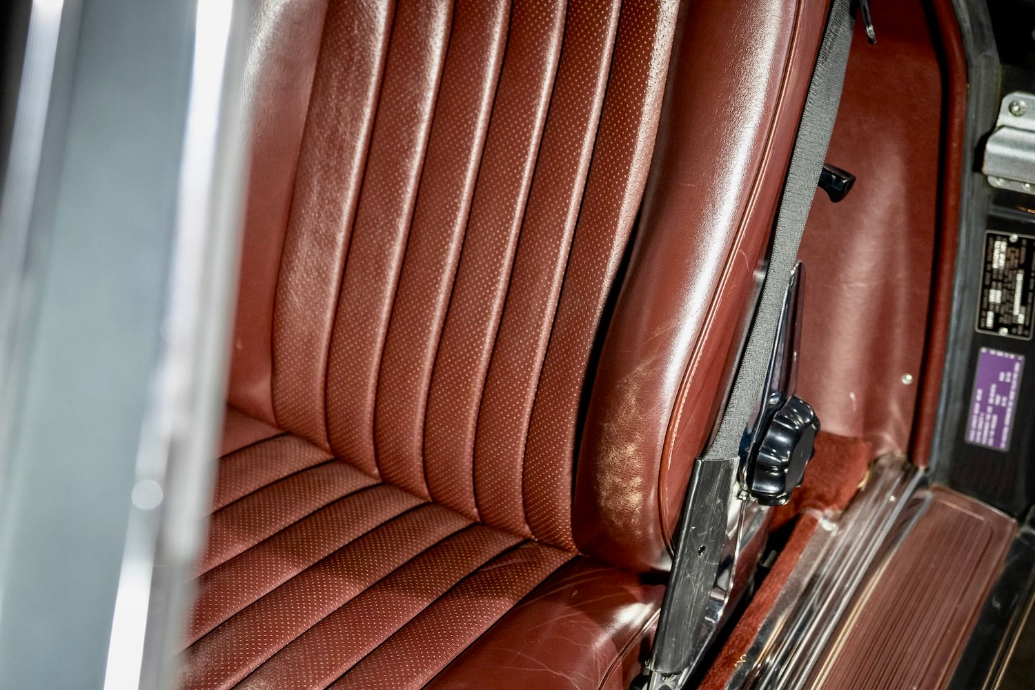 Close-up of a brown leather car seat with a seatbelt.