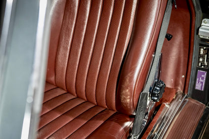 Close-up of a brown leather car seat with a seatbelt.