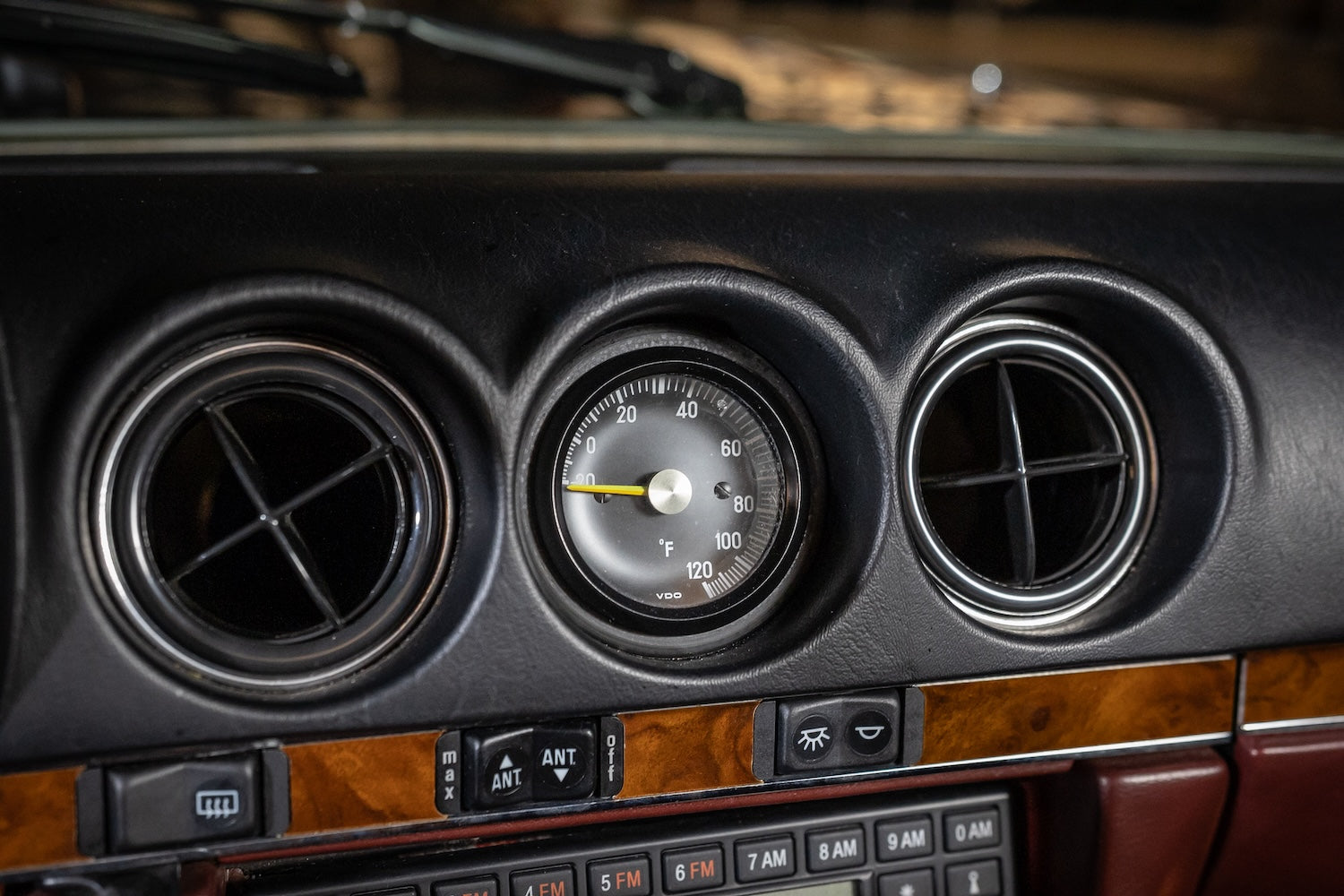 Close-up of a car's dashboard with air vents and temperature gauge.