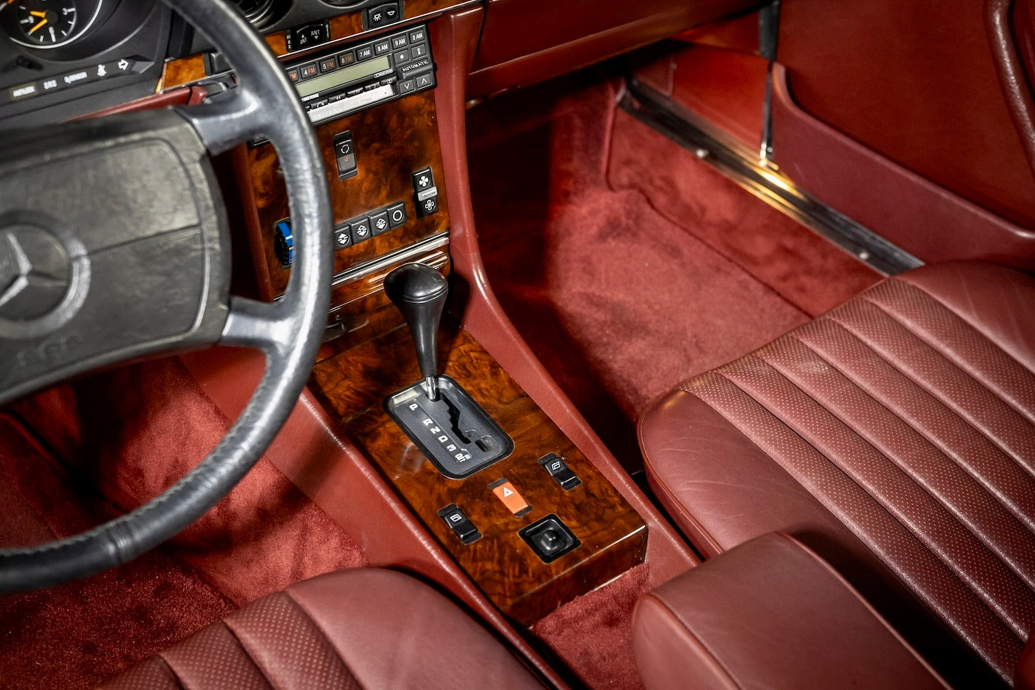 Luxury car interior with brown leather seats and steering wheel, featuring a Mercedes-Benz logo.
