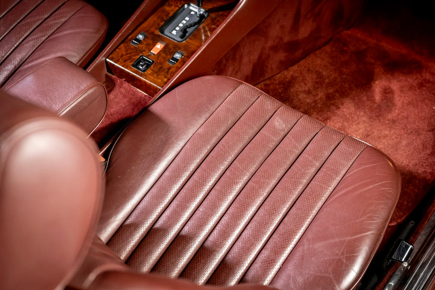 Close-up of a brown leather car seat with wooden paneling.