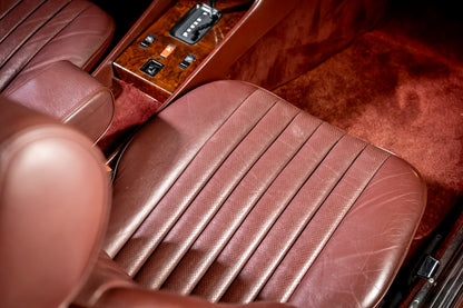 Close-up of a brown leather car seat with wooden paneling.