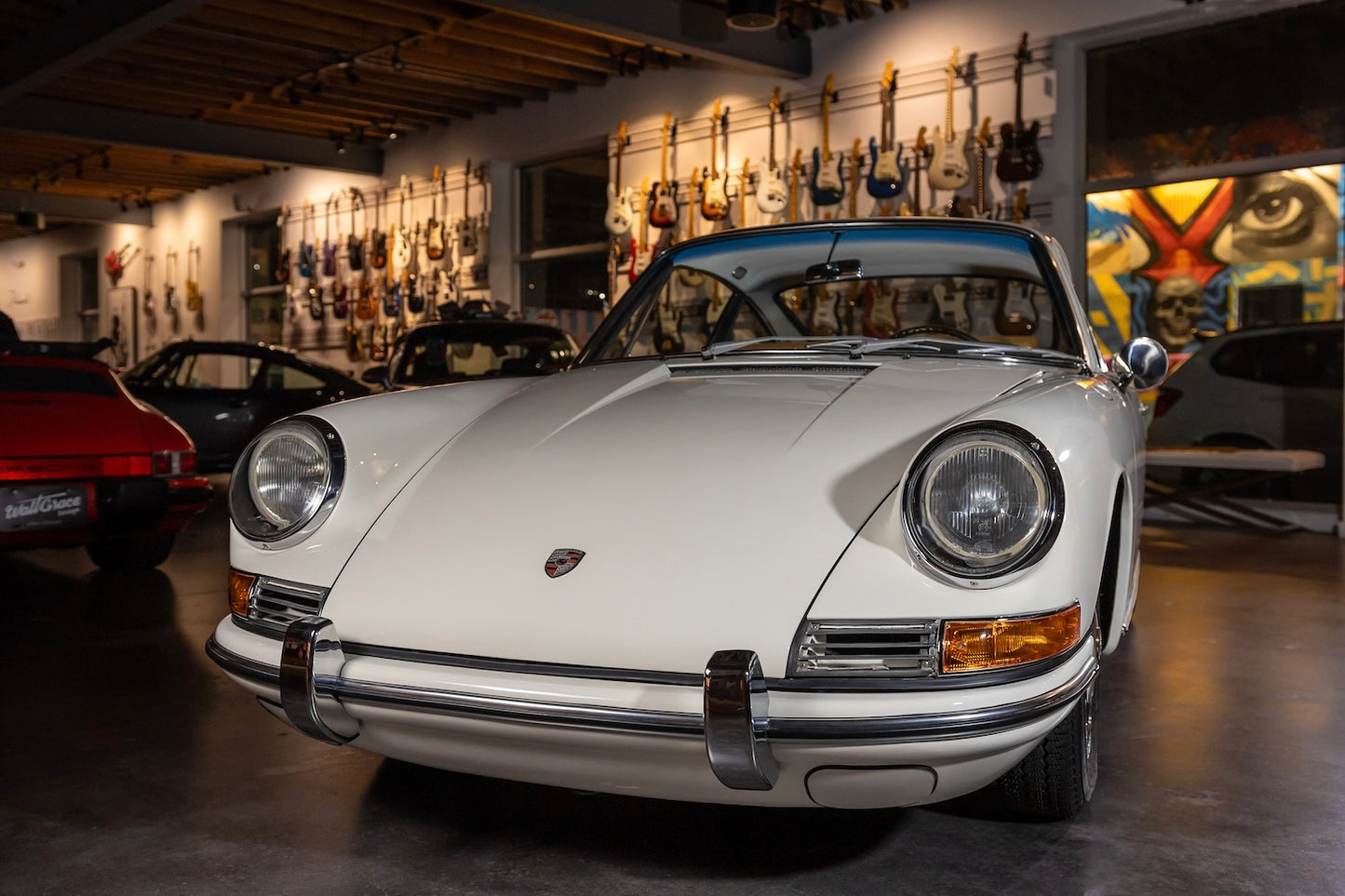 Vintage white Porsche car in a showroom with guitar wall in the background