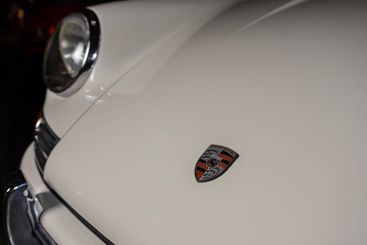 Close-up of a white car with a logo on the hood.