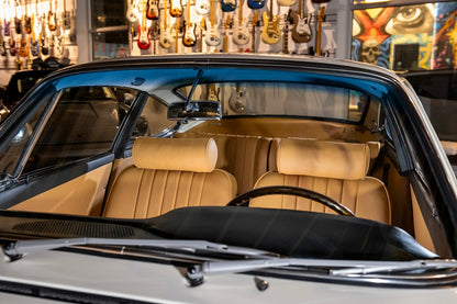 Beige interior of a classic car with guitars in the background