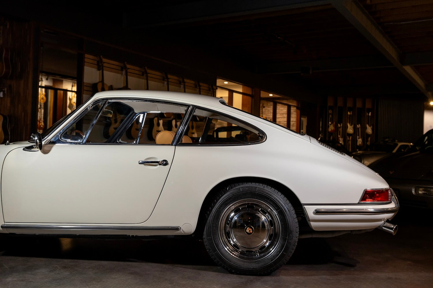 White vintage car parked inside a building with wooden walls.