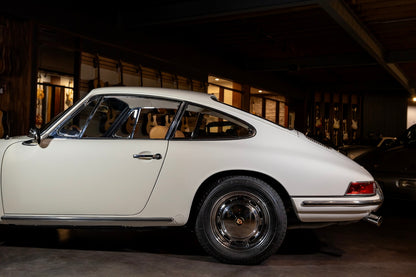 White vintage car parked inside a building with wooden walls.