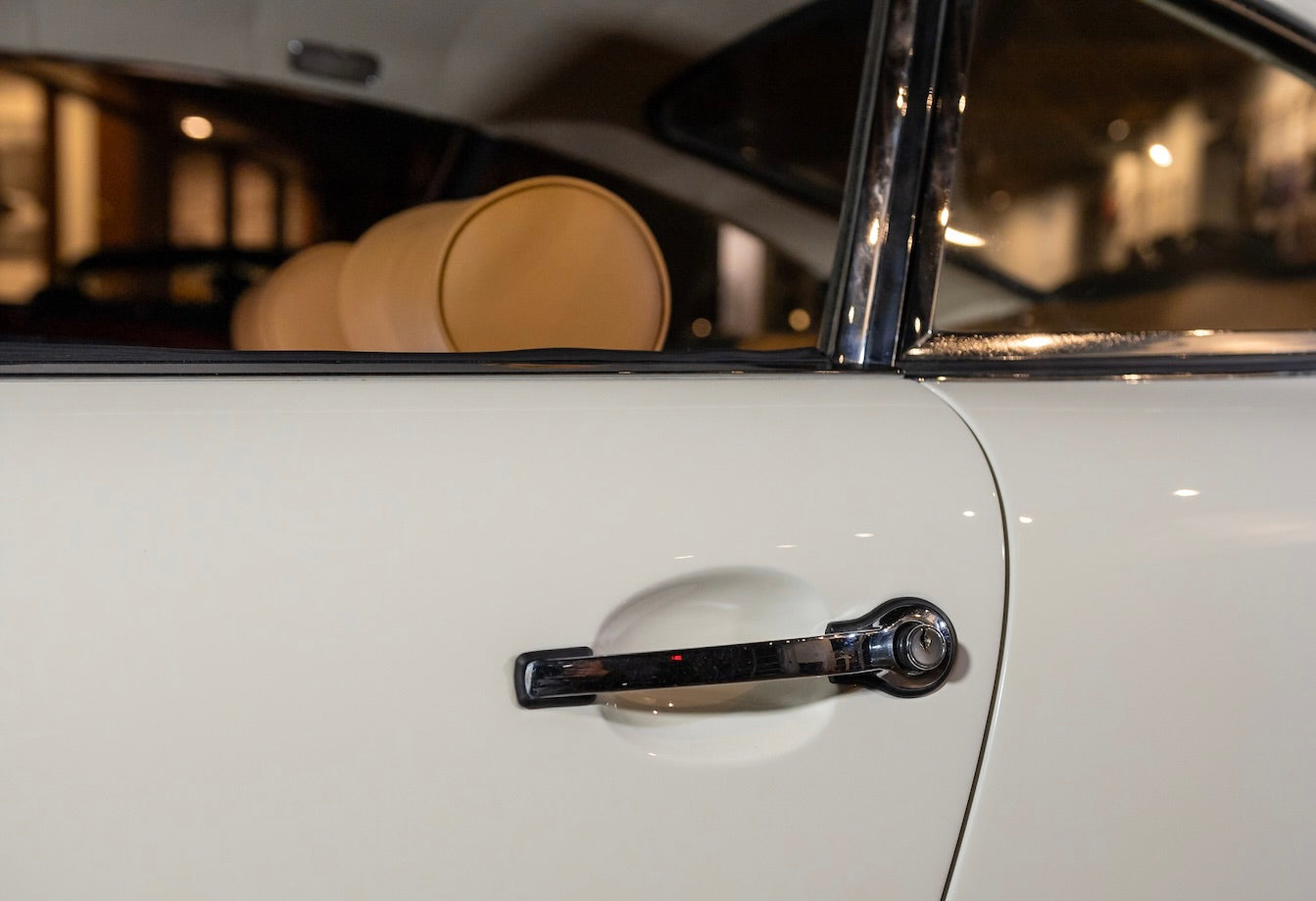 Close-up of a car door handle on a white car with a blurred interior background