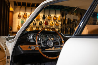 Car interior with wooden steering wheel and dashboard, guitar wall in the background