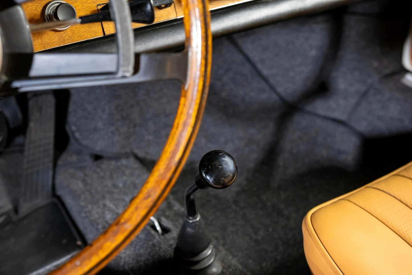 Close-up of a car's interior with a wooden steering wheel and dashboard.