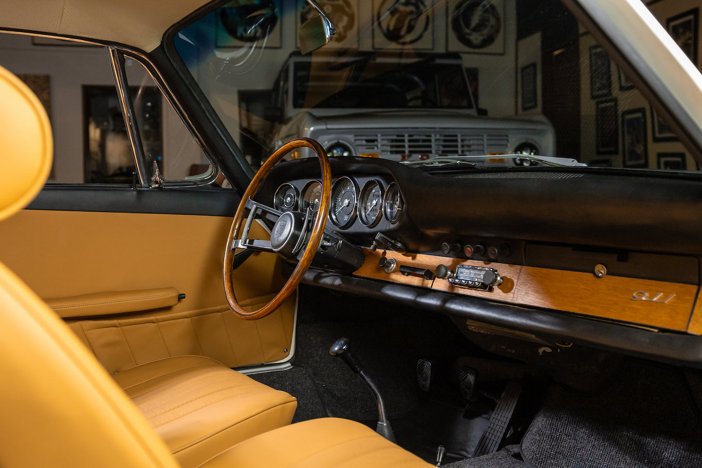 Close-up of a classic car's interior with wooden dashboard and steering wheel.