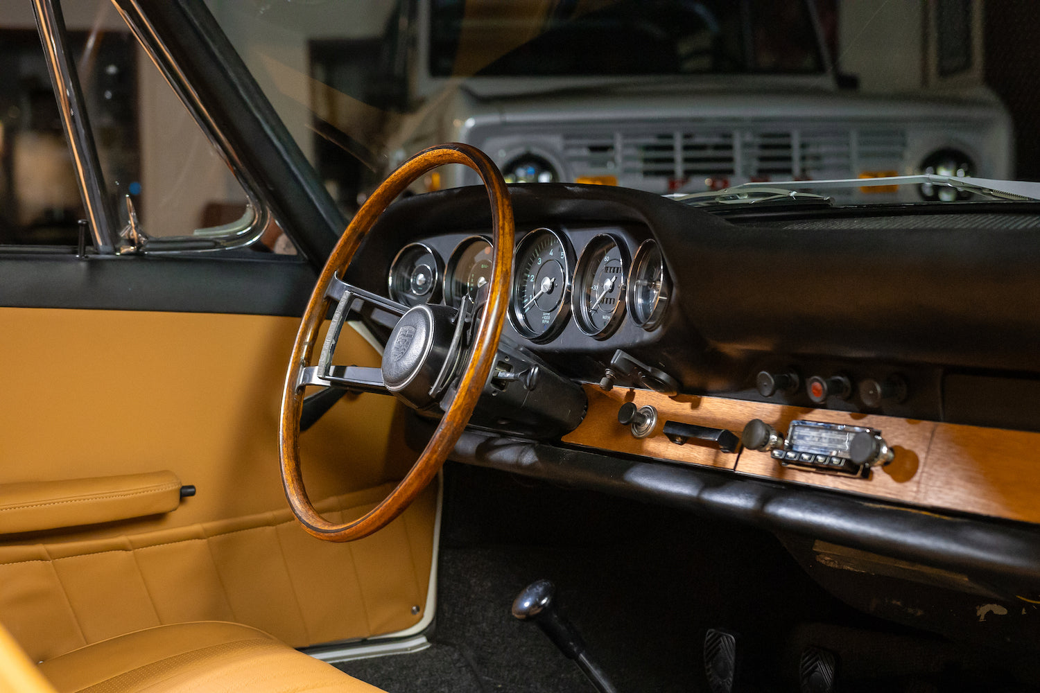 Close-up of a classic car's steering wheel and dashboard with a blurred background.