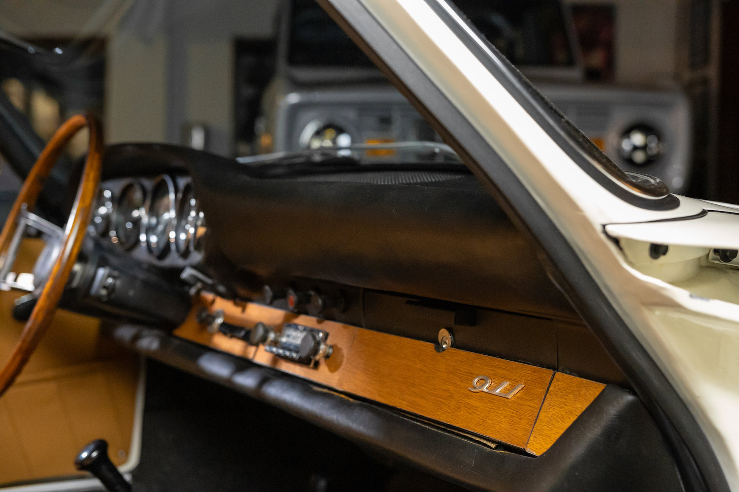 Close-up of a car's interior with wooden panel and 'Gullwing' door handle.