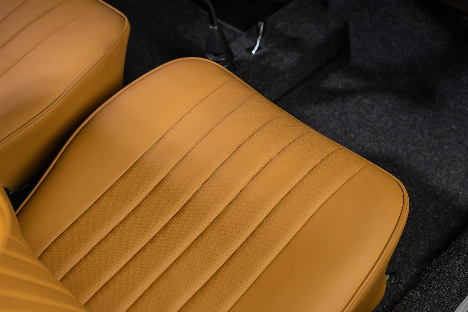 Close-up of brown leather car seats with a dark floor in the background