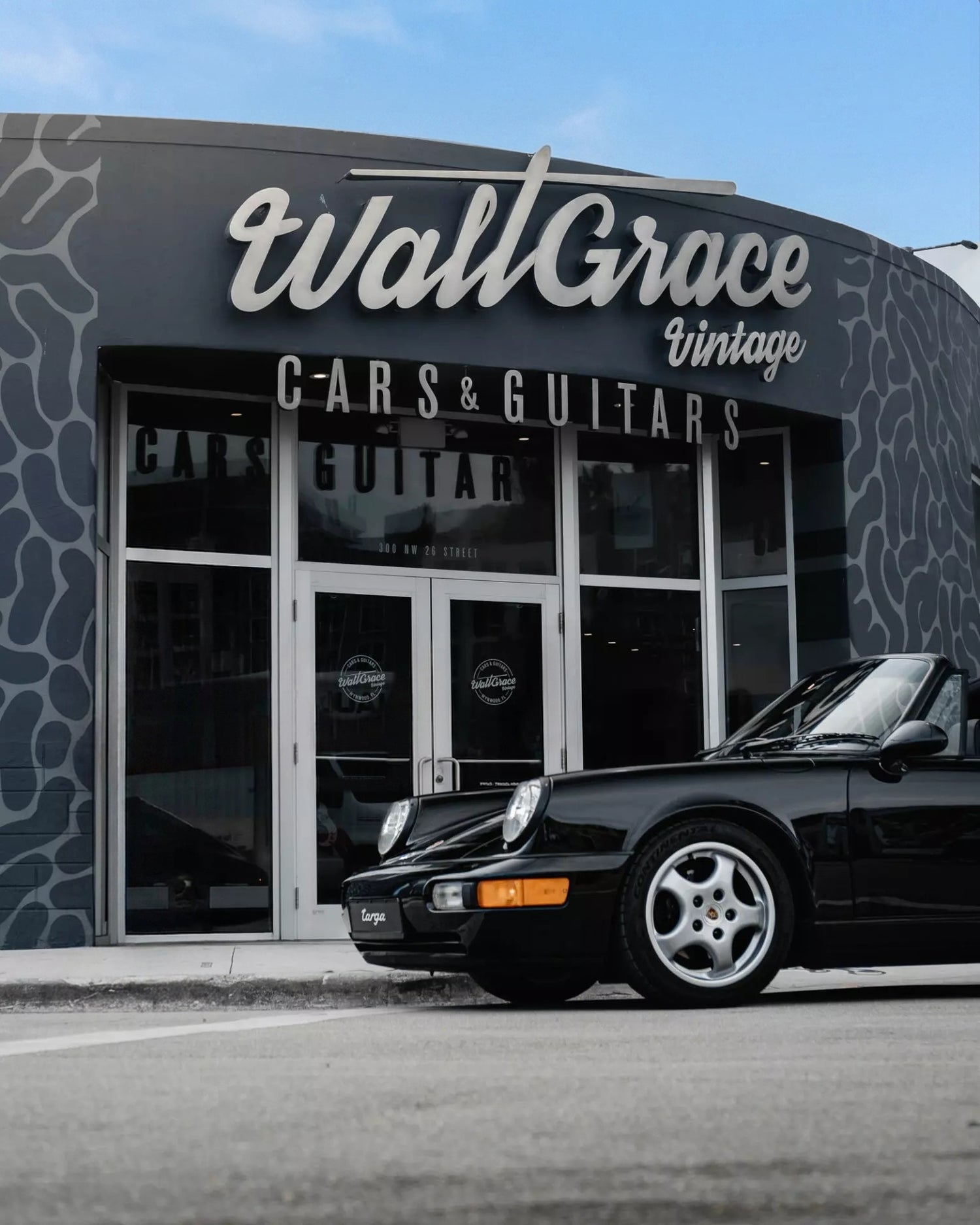Porsche 911 parked in front of a store named 'Walt Grace Vintage Cars & Guitars'.