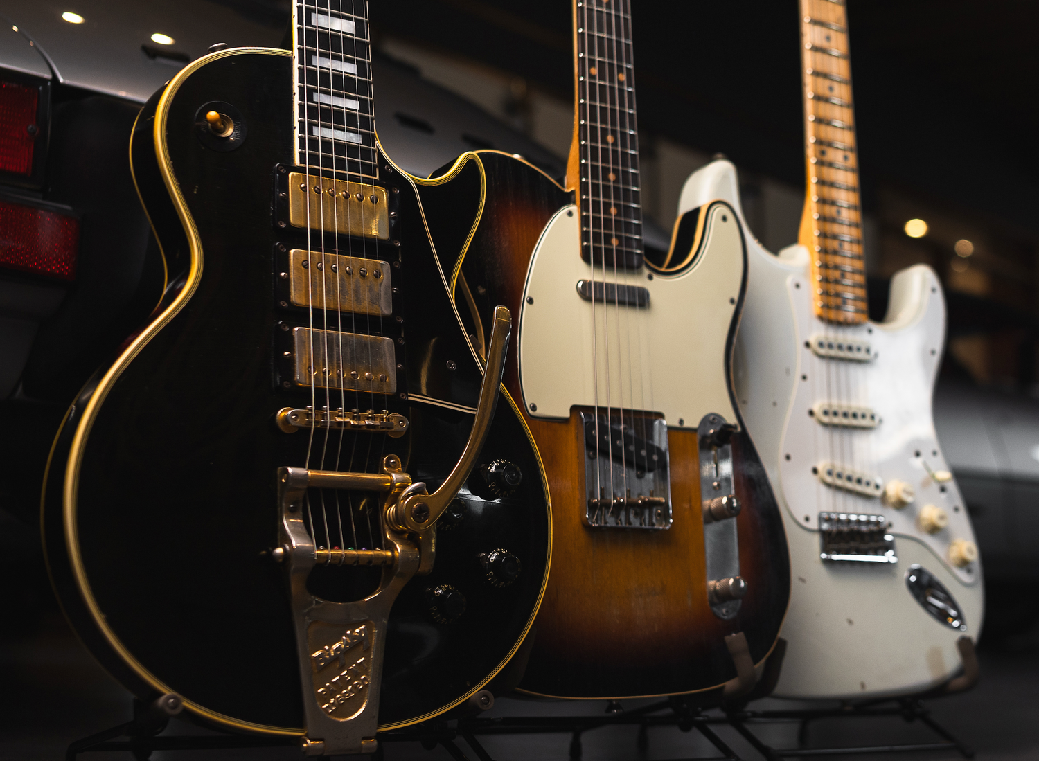 Three electric guitars displayed against a dark background