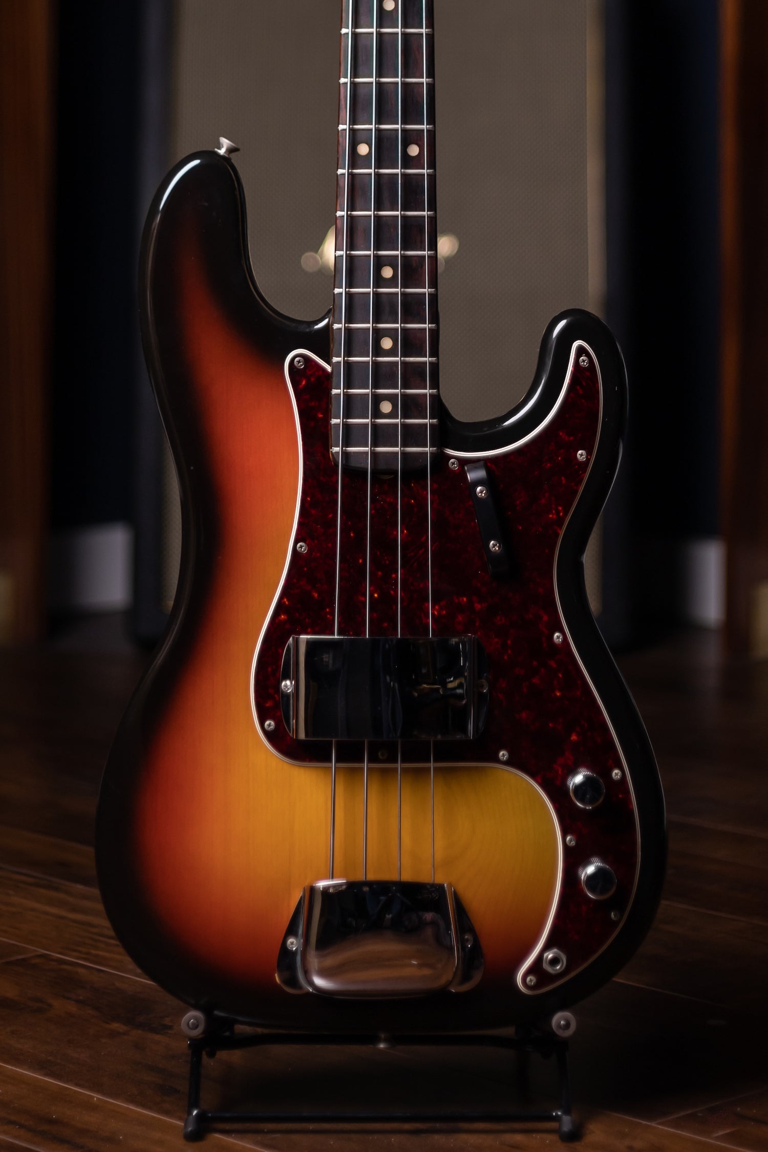 A 1968 Fender Precision Bass in sunburst finish with a solid alder body, maple neck, and rosewood fingerboard, displayed vertically with the headstock facing the camera.
